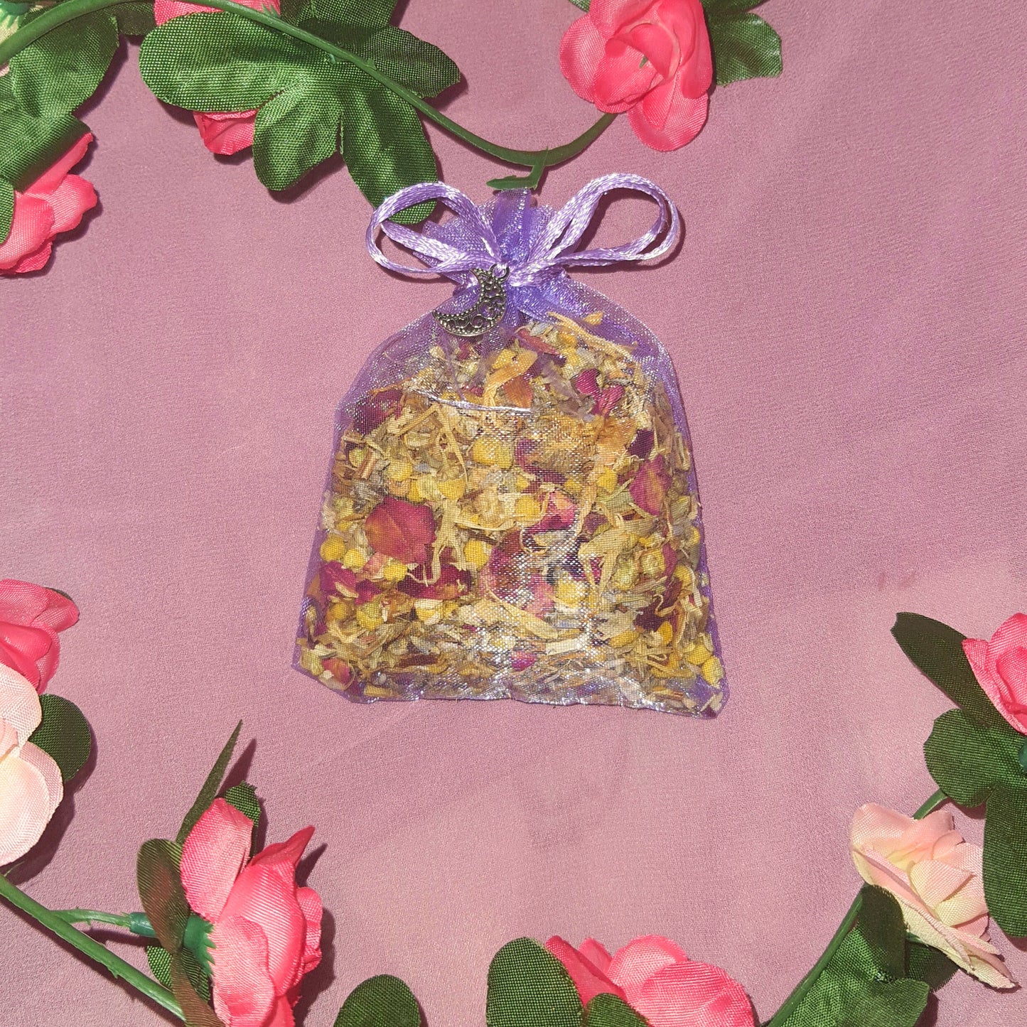 An image of a purple herbal sleep pouch, delicately crafted and adorned with a small moon charm. The pouch exudes a calming aura, featuring a blend of soothing herbs known for their sleep-inducing properties. The moon charm dangles gracefully, adding a touch of enchantment to this handmade creation designed to promote restful slumber.