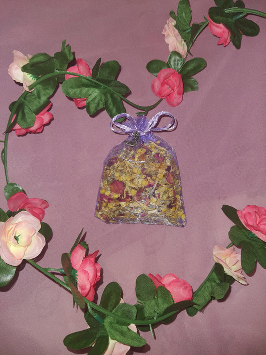  "An image of a purple herbal sleep pouch, delicately crafted and adorned with a small moon charm. The pouch exudes a calming aura, featuring a blend of soothing herbs known for their sleep-inducing properties. The moon charm dangles gracefully, adding a touch of enchantment to this handmade creation designed to promote restful slumber."