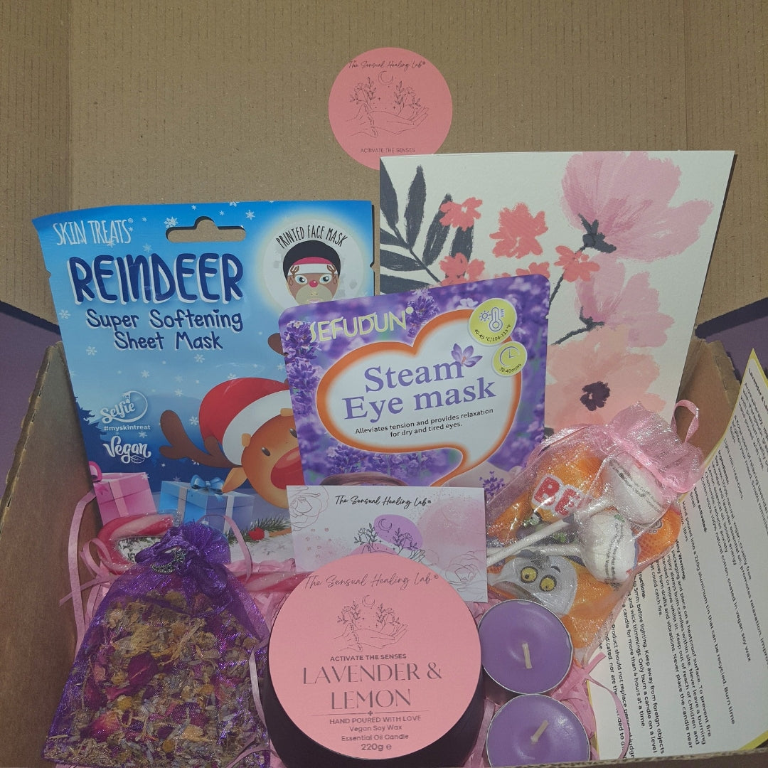 Luxury selfcare gift box of assorted aromatherapy, skincare and wellness products including festive reindeer sheet masks, handmade soy wax candles, herbal sleep pouches and treats in a box.