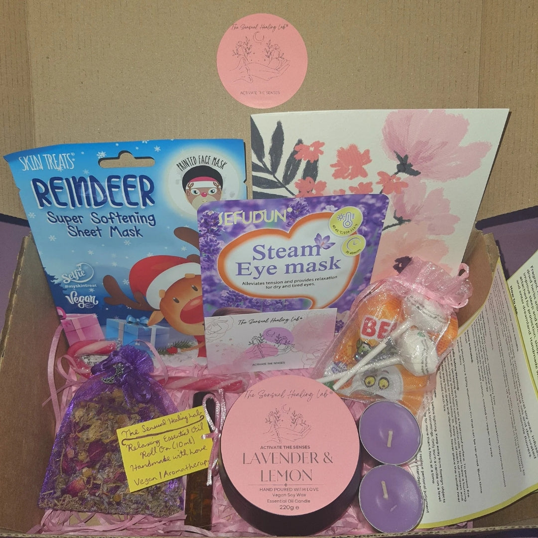 Luxury selfcare gift box of assorted aromatherapy, skincare and wellness products including festive reindeer sheet masks, handmade soy wax candles, herbal sleep pouches, lavender essential oil roller and treats in a box.