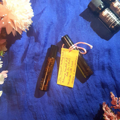 Two small essential oil roller bottles with a yellow label on a blue textured surface.