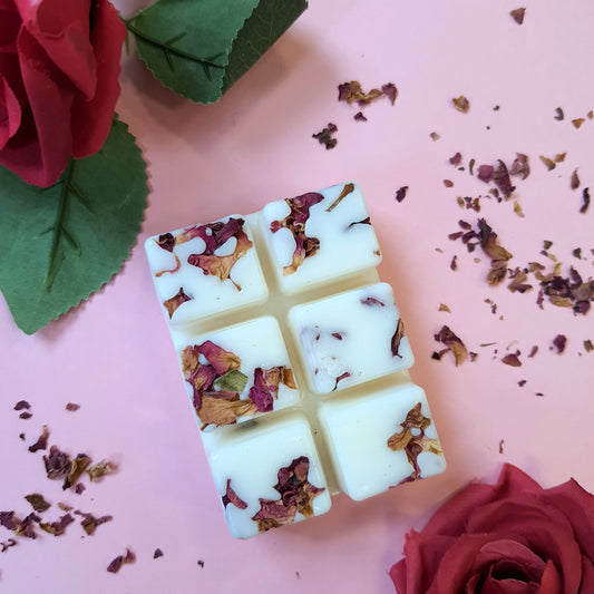 Rose & Sandalwood soy wax melts adorned with dried rose petals, a sensual spring scene with a light pink background, and wax melts surrounded by beautiful rose petals.
